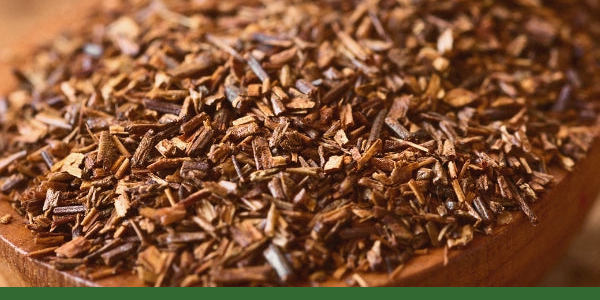 Loose rooibos in a wooden bowl with a Gaia Garden green line along the bottom