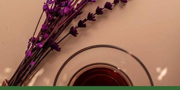Dried lavender beside a glass cup of herbal tea.