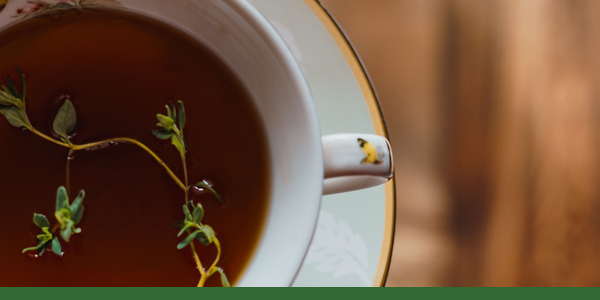 Cup of thyme tea with fresh thyme sprigs.