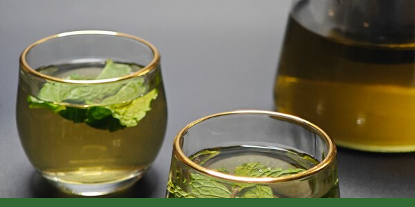 Peppermint vs. spearmint tea served in clear glasses and a teapot, with fresh mint leaves and a Gaia Garden green line along the bottom